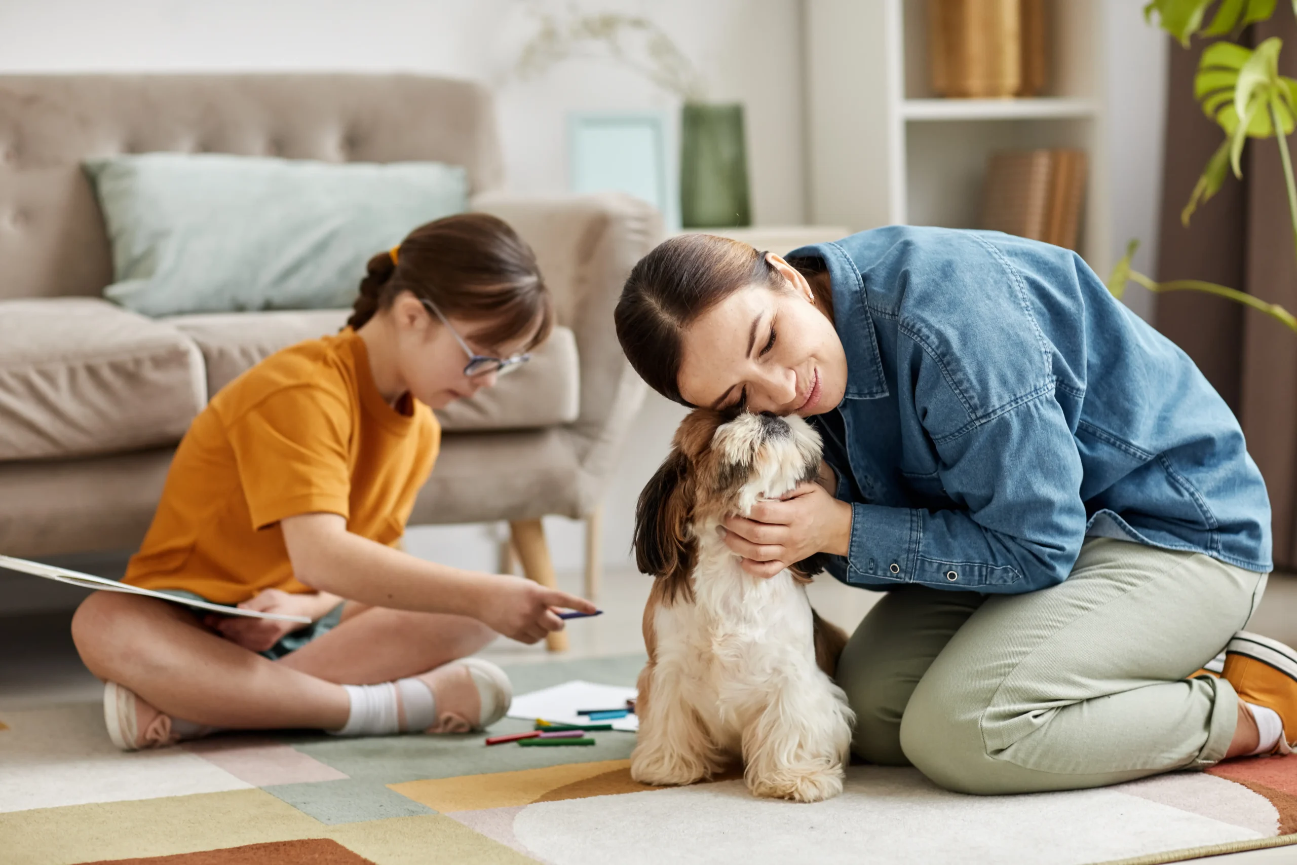 Mujer con su hija y el perro jugando en la alfombra